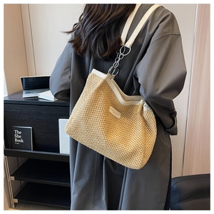 Detail of summer straw woven tote bag featuring white leather trim and metal chain strap