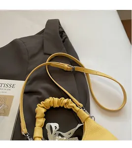 Detail of yellow pleated handle bag with adjustable strap and pearl lace charm