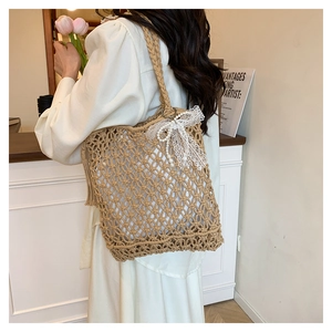 Detail of hand-woven straw bag with elegant lace bow and pearl chain decoration