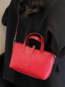 Red textured leather handbag for women shown with model in a classic black blazer