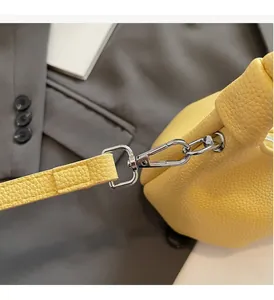 Detailed macro view of glossy silver metal hardware on a yellow lychee leather bag