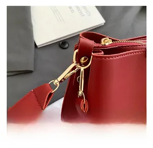 Close-up of red pebbled leather bag with premium gold metal hooks and zipper details