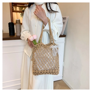 Detail of hand-woven hollow mesh tote bag with white lace bow and pink tulip accessories