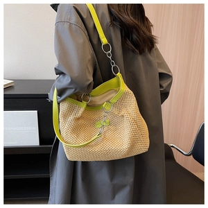 Detail of hand-woven straw tote with neon green leather straps and silver ring accents