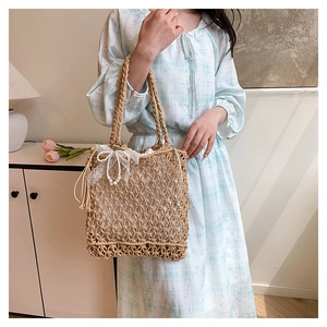 Detail of woven straw tote with lace bow, pearl charm, and drawstring lining