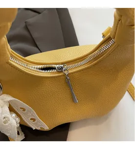 Close-up of yellow hobo bag featuring litchi grain texture and a white lace pearl bow