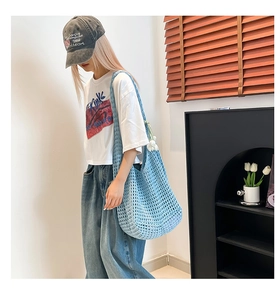 Detail view of light blue hollow crochet woven shoulder bag with intricate mesh pattern