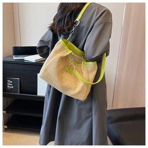 Detail of straw woven tote with neon green trim and silver metal chain strap detail