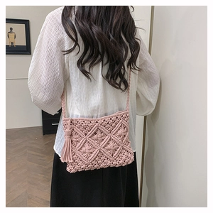 Détail du sac à bandoulière en macramé rose avec pompons et motif tissé à la main