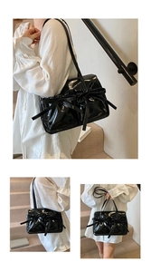 Detail view of the black glossy leather shoulder bag featuring decorative ribbon bows