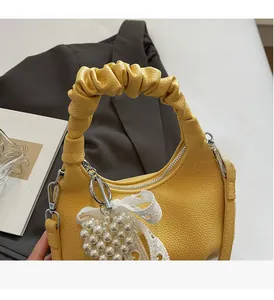 Detail of yellow lychee leather bag with pearl heart charm and lace bow decor