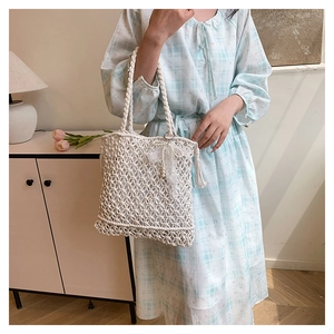 Detailed close-up of white handmade woven cotton bag with lace bow and tassel accents