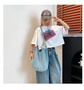 Detail of light blue woven knit tote bag with delicate white tulip floral charm
