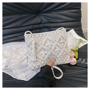 Close-up of handmade white cotton rope woven bag with bohemian tassels and diamond pattern