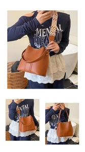 Detail of brown bucket bag with geometric patterned wide strap and gold hardware