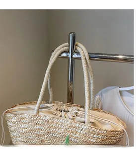 Detail of hand-woven straw bag featuring a beige drawstring closure and reinforced handle