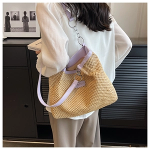 Detail of beige straw tote bag with lavender leather strap and silver metal chain detail