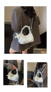 Detail of light blue pleated handle bag featuring pearl heart charm and dotted ribbon