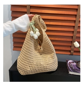 Close-up of beige hollow woven tote bag with white tulip charm and mesh texture