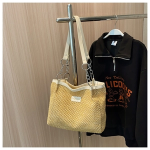 Detail of straw tote bag with silver chain handles and woven texture for summer
