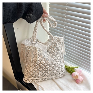 Detail of white hand-woven mesh tote bag with lace bow, pearl chain and tassel charms