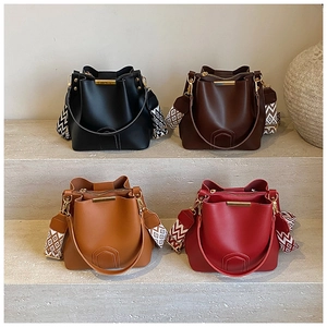Detail of four stylish bucket bags in black, coffee, brown, and red with ethnic straps