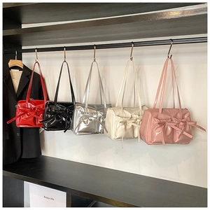 Showcase of five glossy bow-knot shoulder bags in red, black, silver, white and pink