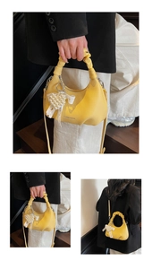 Detail of yellow mini bag with pleated cloud handle and pearl heart charm accessory