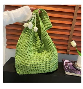 Close-up of green crochet woven bag featuring intricate hollow mesh and tulip charms