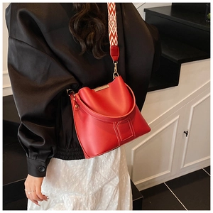 Detail view of red leather bucket bag with geometric woven strap on model's shoulder