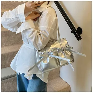 Close-up of metallic silver shoulder bag featuring dual pockets and ribbon bow detail
