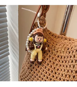 Close-up of a cute cartoon doll charm with pearl beads on a woven bucket bag