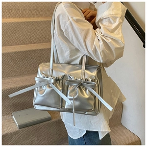 Detail view of silver bow-knot pleated shoulder bag showing metallic leather texture