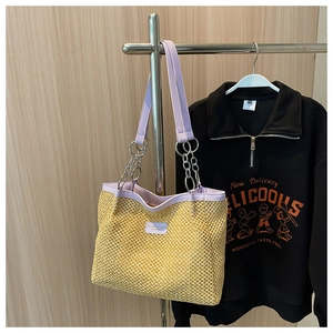 Detail of handmade straw tote with purple faux leather trim and chain shoulder strap
