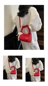 Detail view of red pleated handle handbag with pearl lace charm and chain strap