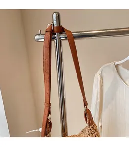 Detail of adjustable brown leather shoulder strap on a straw woven bucket bag