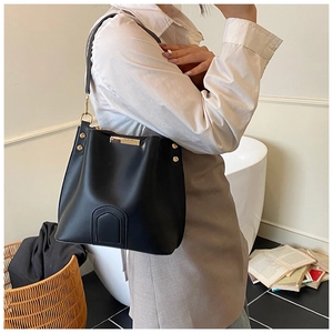 Close-up of black leather bucket bag featuring gold studs and elegant stitching detail