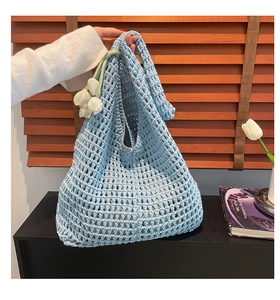 Detail of light blue crochet mesh bag with delicate tulip pendant and woven texture