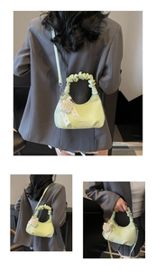 Macro detail of a light green pleated handbag with a lace bow and pearl charm