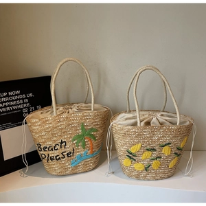 Detailed macro view of straw tote bags featuring colorful palm and lemon embroidery