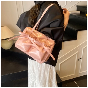 Detail of pink patent leather shoulder bag with a large bow showing glossy texture