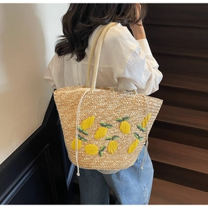 Detail of hand-woven straw tote bag with lemon embroidery and woven rope handle