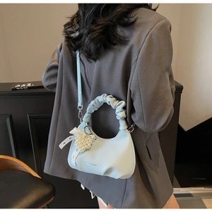 Detail of light blue textured leather handbag with lace bow and heart pearl pendant