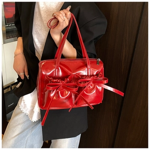 Detail of red patent leather handbag with pleated pockets and decorative bows