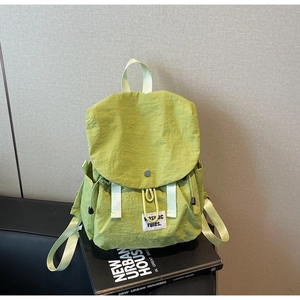 Close-up of light green backpack with crinkled nylon fabric texture and decorative straps