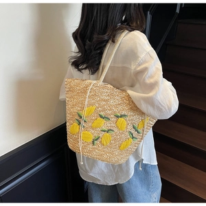 Detailed view of handmade straw tote with 3D lemon embroidery and drawstring closure