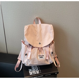 Detailed view of pink nylon backpack with drawstring closure and metal buckle on books