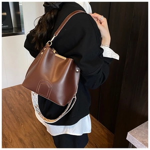 Detail of brown leather bucket bag with gold hardware and two interchangeable straps