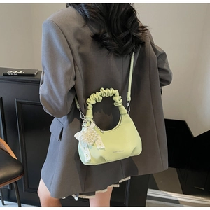 Lime green pleated crescent bag featuring pearl lace charm and fashion bags logo on dark suit