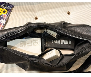 Close-up of the spacious interior of a black pleated hobo bag showing large storage capacity